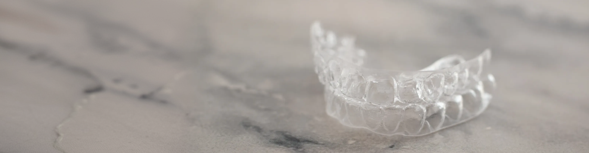 Clear Invisalign aligners resting on a countertop, showcasing custom-made removable trays designed to gradually straighten teeth with a nearly invisible appearance.